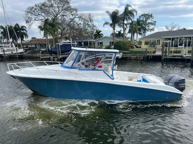 Slide: The Image of 2008 Fountain 33 SFC Sportfish Cruiser on water, blue hull, palm trees in background. - 1