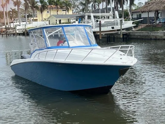 Slide: The Image of 2008 Fountain 33 SFC Sportfish Cruiser in marina, blue hull, enclosed cockpit. - 2