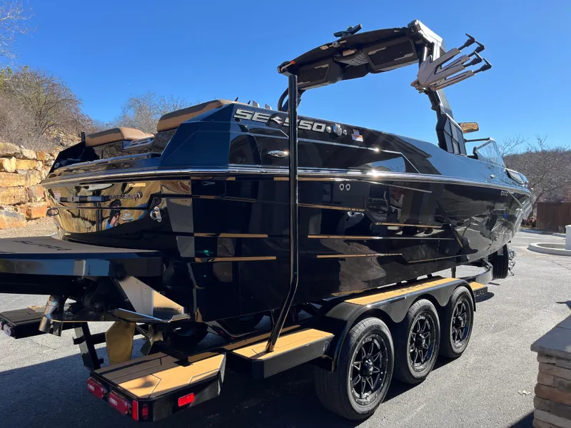 Slide: The Image of 2025 Supra SE boat on trailer, sleek black design, outdoor setting. - 2