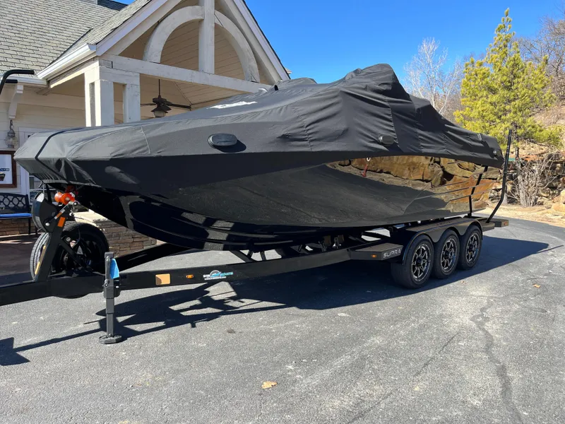 Slide: The Image of 2025 Supra SE boat covered on a trailer, parked in a driveway. - 28