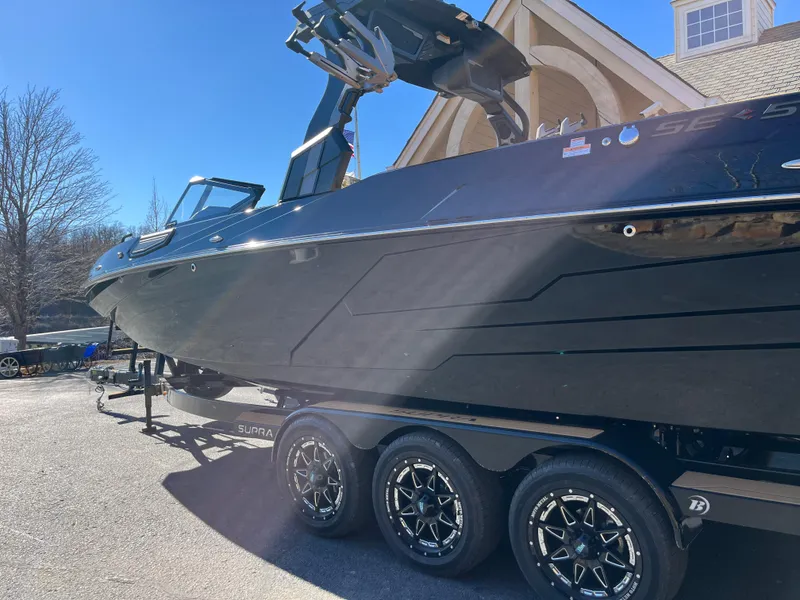 Slide: The Image of 2025 Supra SE boat on trailer, sleek black design, parked outdoors. - 3