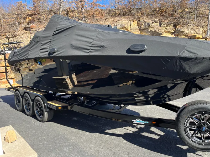 Slide: The Image of 2025 Supra SE boat covered on a trailer, parked outdoors. - 30