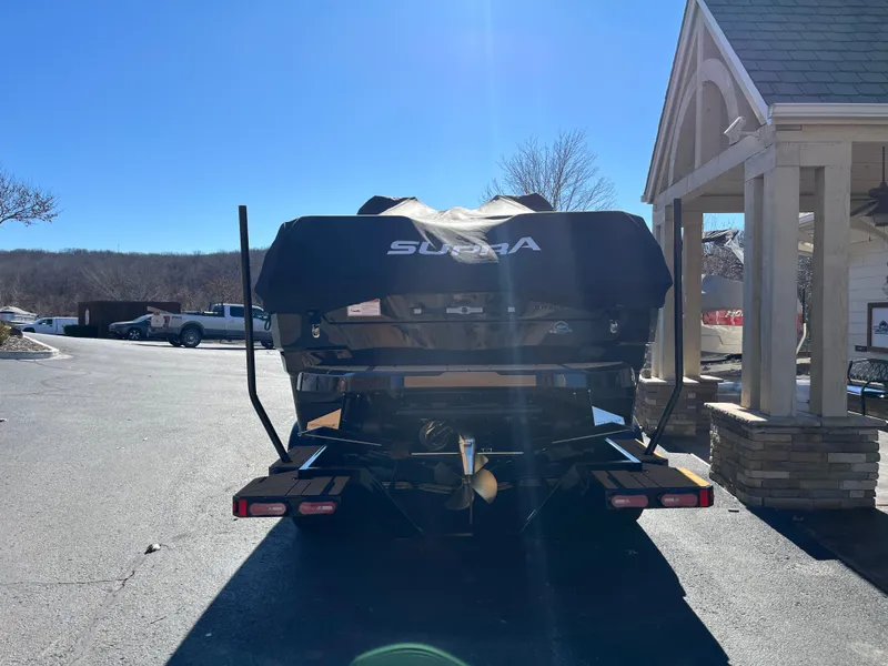Slide: The Image of 2025 Supra SE boat on trailer, parked outdoors under clear blue sky. - 32