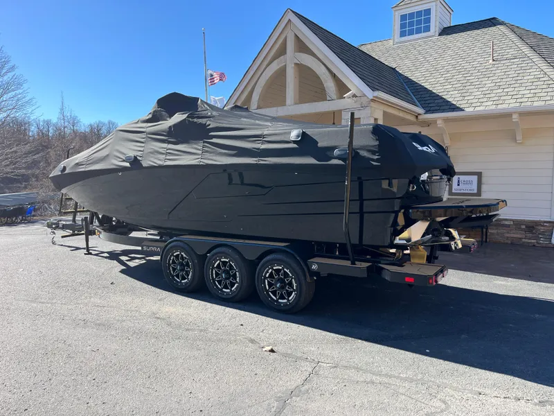 Slide: The Image of 2025 Supra SE boat covered on a trailer, parked near a building. - 33