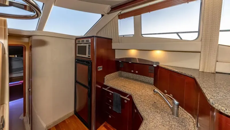 Slide: The Image of Interior of 2006 Sea Ray 44 Sedan Bridge yacht, featuring a modern kitchen with wood cabinetry. - 4