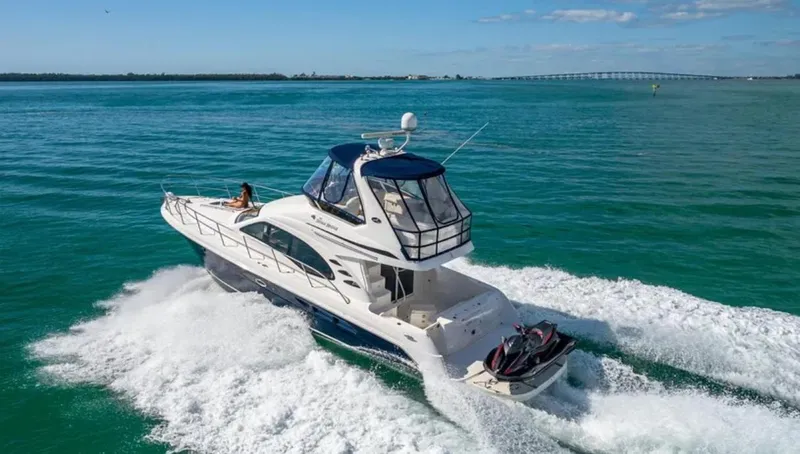 Slide: The Image of 2006 Sea Ray 44 Sedan Bridge yacht cruising on open water, clear skies above. - 9