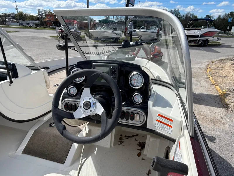 Slide: The Image of 2015 Nitro Z-7 Sport boat dashboard with steering wheel and gauges, parked outdoors. - 12