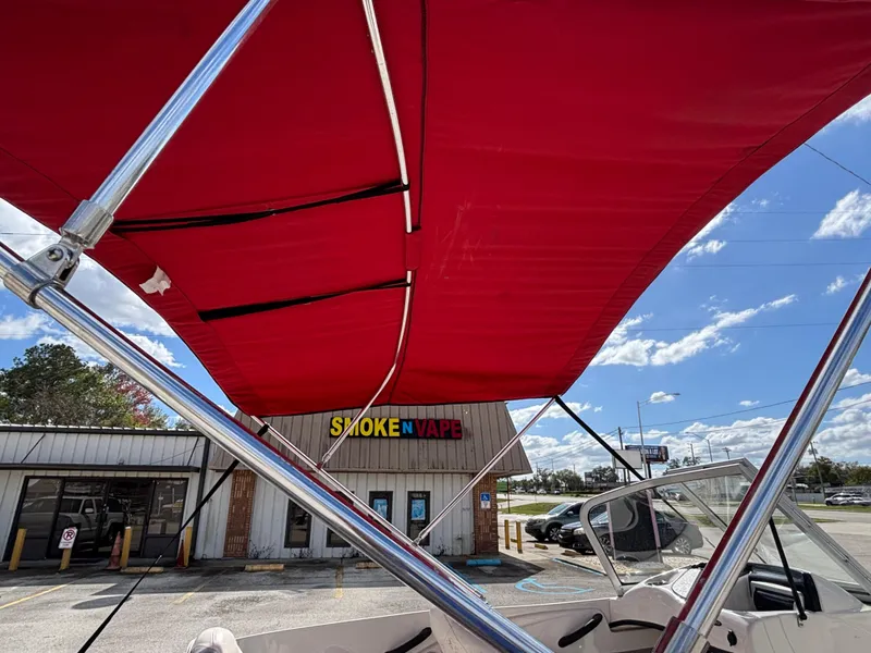 Slide: The Image of Red canopy on 2014 Nitro Z-7 boat, parked near a store under a blue sky. - 19