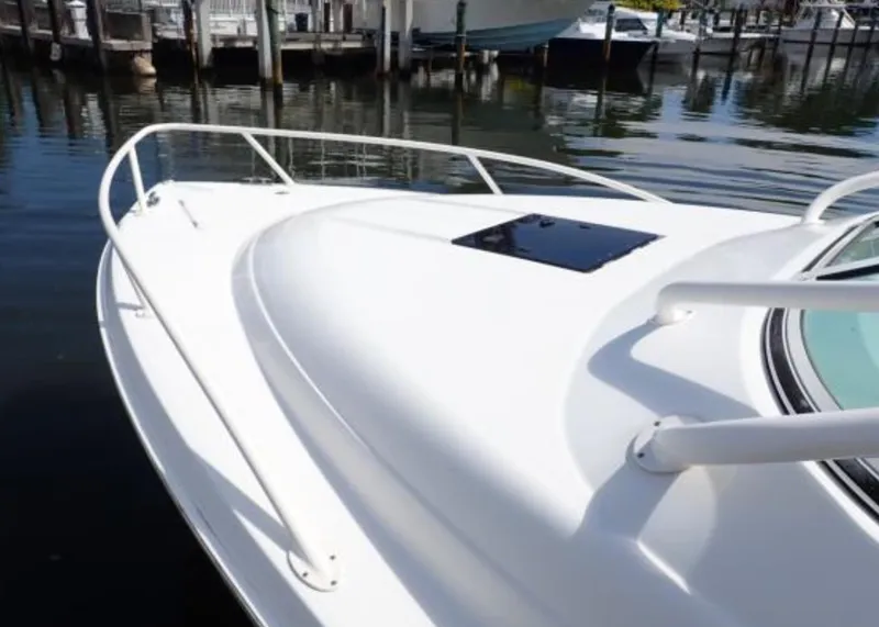 Slide: The Image of 2016 Jupiter 34 LX boat bow, docked in marina, featuring sleek white design. - 2