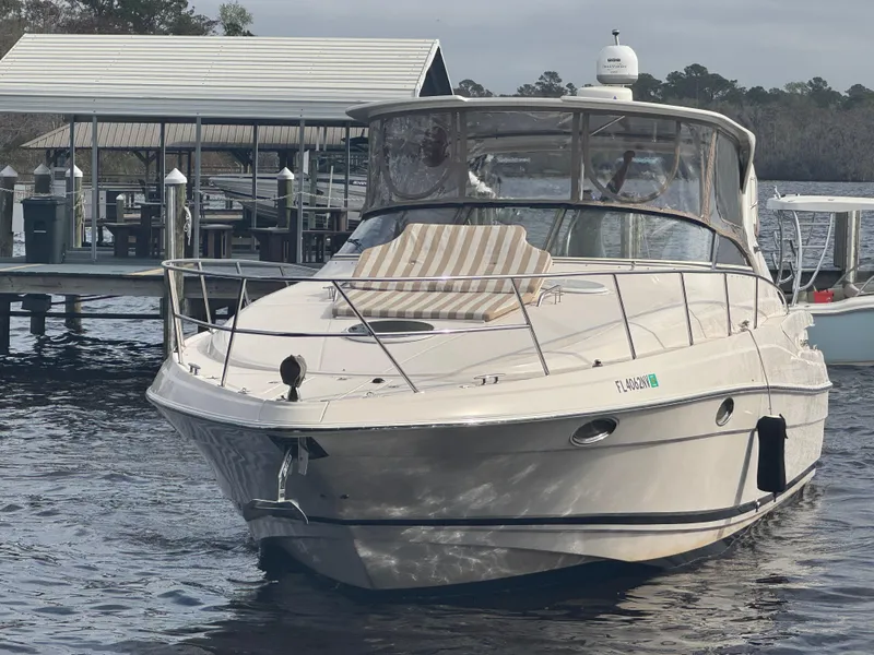 Slide: The Image of 2005 Regal 3560 Commandor boat docked near a serene lakeside setting. - 3