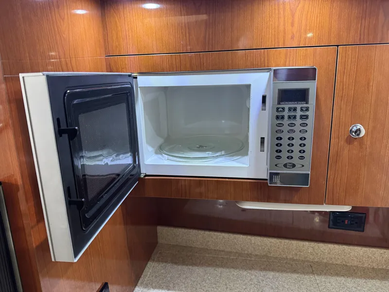 Slide: The Image of Open microwave in 2005 Regal 3560 Commodore yacht kitchen, wood paneling background. - 35