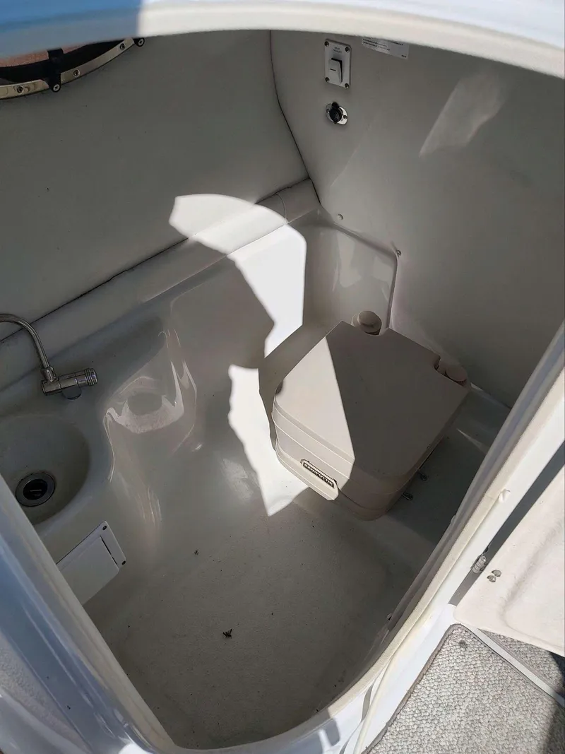 Slide: The Image of 2006 Crownline 270 BR boat interior with compact bathroom and portable toilet. - 12