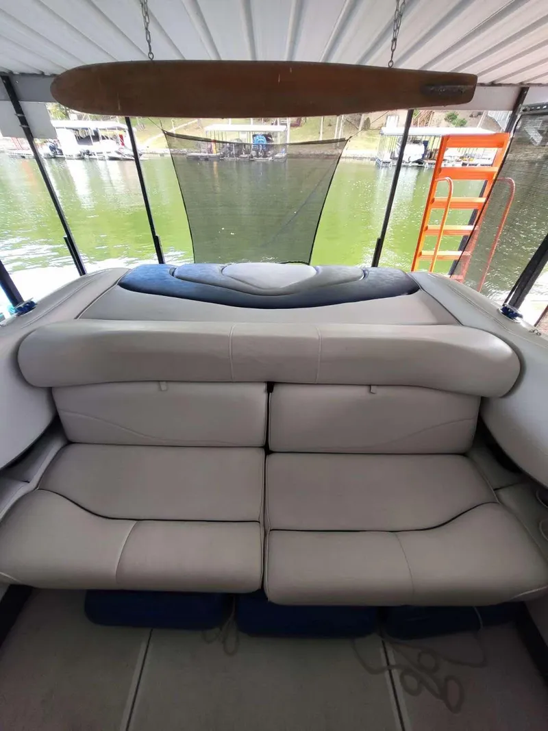 Slide: The Image of 2001 Crownline 248 BR boat interior with cushioned seating, docked by a lake. - 12
