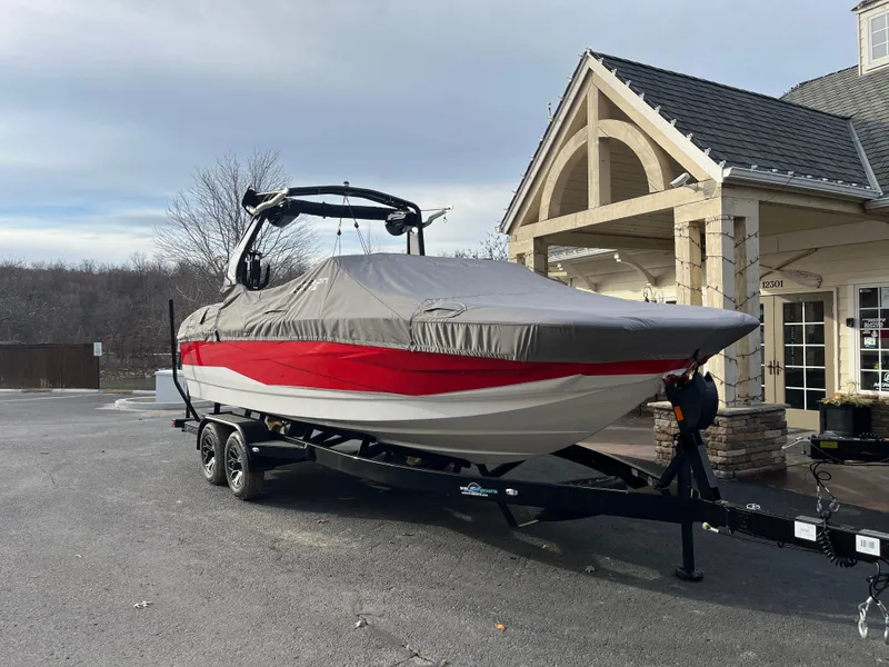Slide: The Image of 2025 Centurion NV233 boat on trailer, covered, parked near a building. - 11
