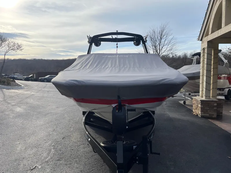 Slide: The Image of 2025 Centurion NV233 boat covered and parked on a trailer in a driveway. - 12