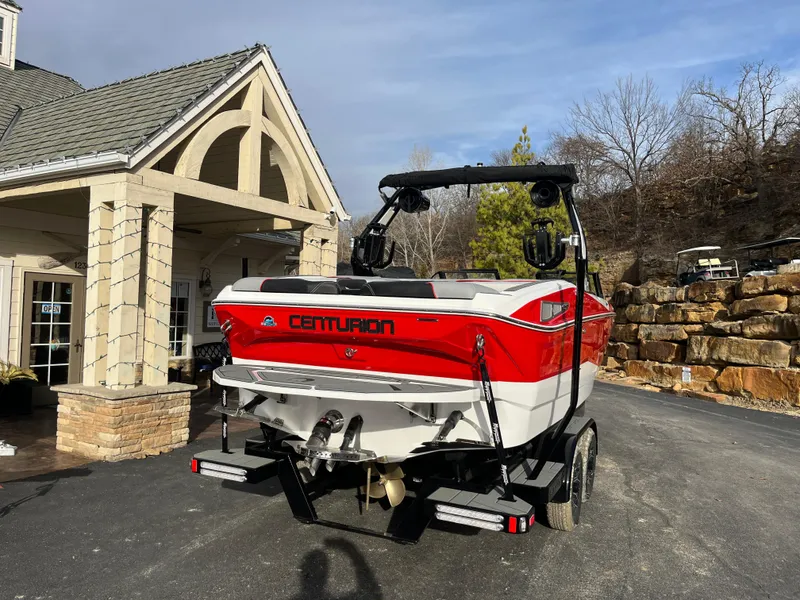 Slide: The Image of 2025 Centurion NV233 boat, red and white, parked near a building on a sunny day. - 4
