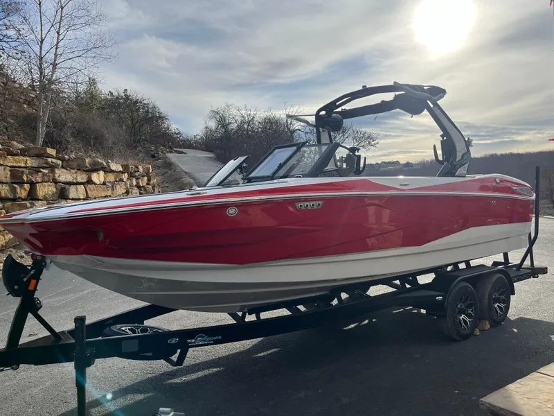 Slide: The Image of Red 2025 Centurion NV233 boat on trailer under sunny sky. - 7