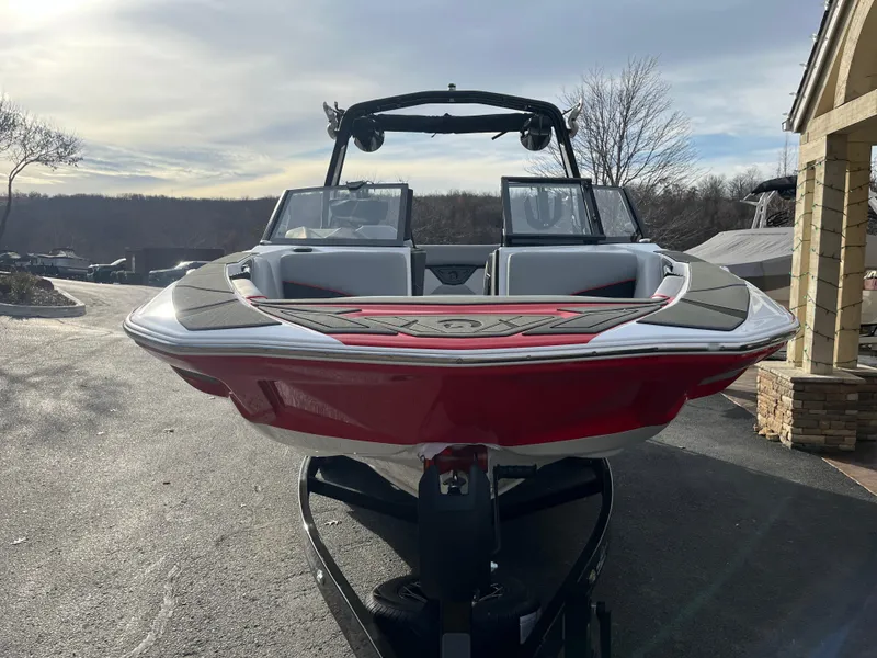 Slide: The Image of 2025 Centurion NV233 boat with red hull on trailer, parked outdoors. - 9