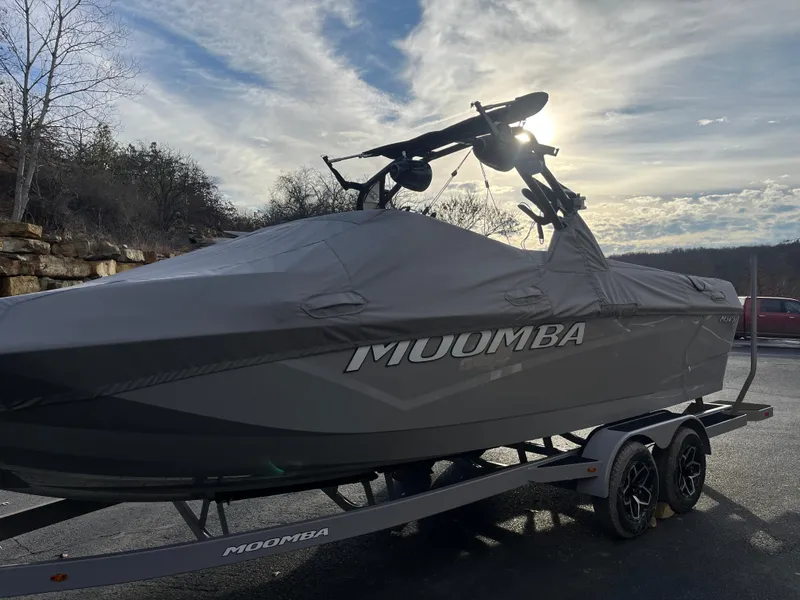 Slide: The Image of 2025 Moomba Makai boat covered on trailer, parked outdoors under cloudy sky. - 9