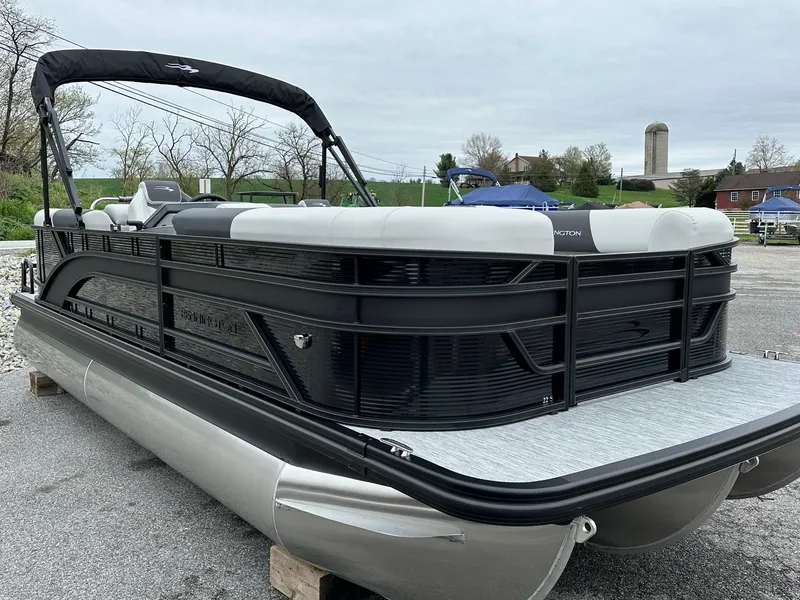 Slide: The Image of 2025 Bennington 22 SSR Quad Bench Tritoon with Yamaha F-150HP, sleek design, parked outdoors. - 22