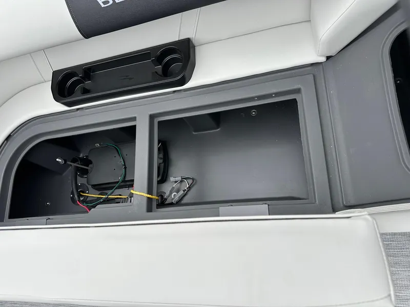 Slide: The Image of 2025 Bennington 22 SSR Tritoon storage compartment with cup holders and wiring details. - 31