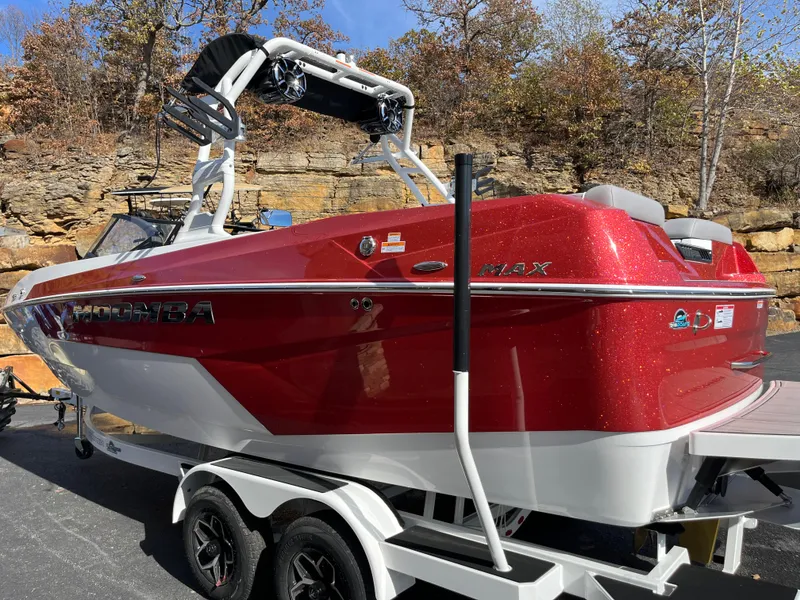 Slide: The Image of 2025 Moomba Max boat in red on a trailer, parked outdoors. - 2