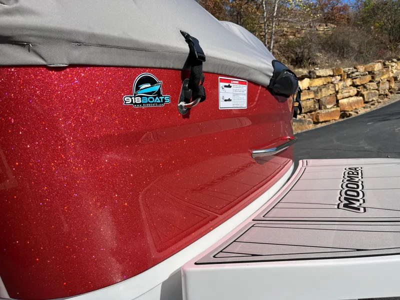 Slide: The Image of 2025 Moomba Max boat with red glitter finish and covered deck, parked outdoors. - 5