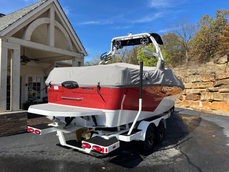 Slide: The Image of 2025 Moomba Max boat with cover, parked on a trailer near a house. - 7