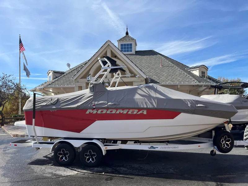 Slide: The Image of 2025 Moomba Max boat with cover on trailer, parked in front of a building. - 8