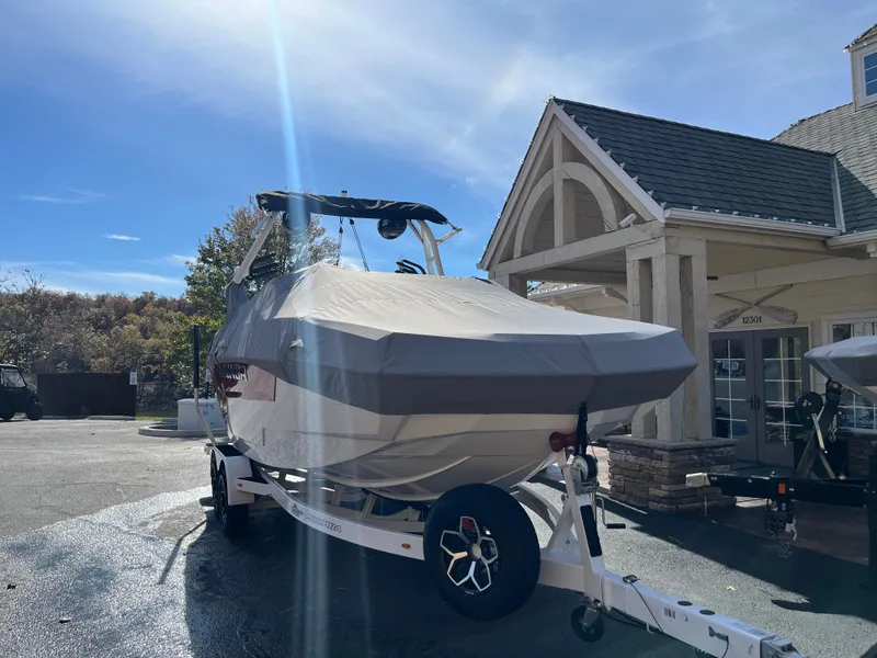 Slide: The Image of 2025 Moomba Max boat on trailer, covered, parked near a building under a clear sky. - 9