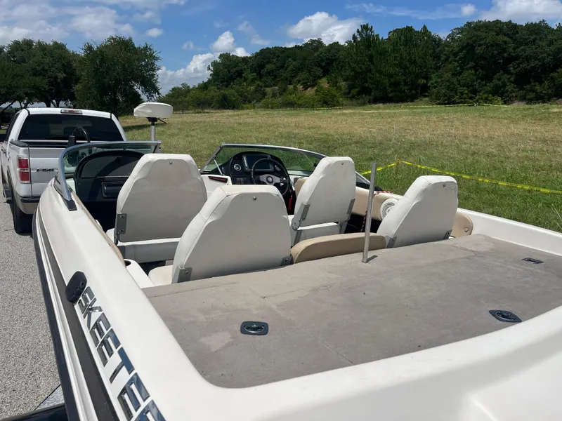 Slide: The Image of 1998 Skeeter 176 SL C boat interior with white seats, parked near a grassy field. - 40