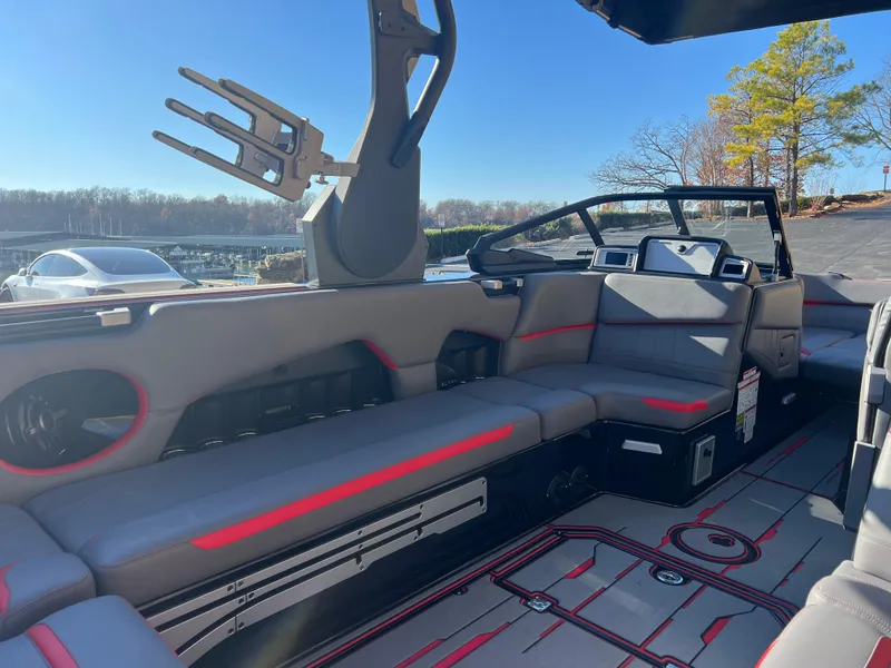 Slide: The Image of 2022 Supra SE boat interior with gray seating and red accents, docked under clear blue sky. - 10