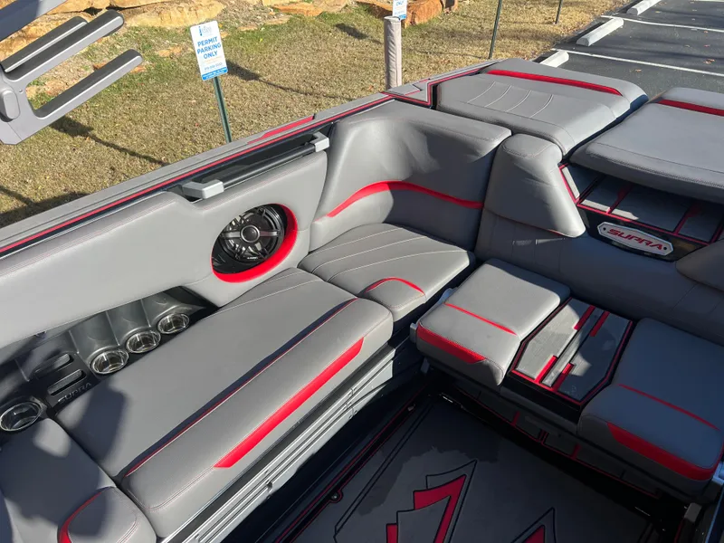 Slide: The Image of 2022 Supra SE boat interior with gray and red seating, speaker, and cup holders. - 12
