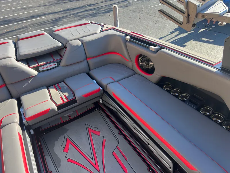 Slide: The Image of 2022 Supra SE boat interior with gray and red seating, cup holders, and stylish design. - 14