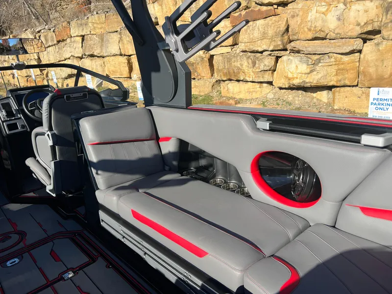 Slide: The Image of 2022 Supra SE boat interior with gray and red seating, near rocky background. - 15