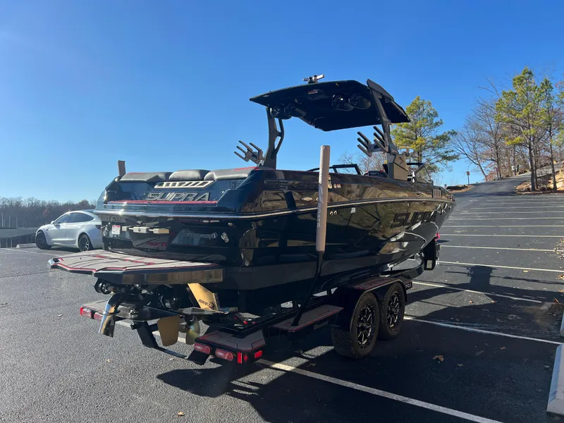Slide: The Image of 2022 Supra SE boat on trailer in parking lot, sunny day, trees in background. - 4