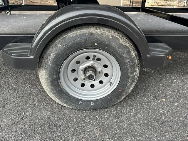 Slide: The Image of 2024 Starcraft LX 20 F trailer wheel on asphalt, featuring a sturdy tire and fender. - 18