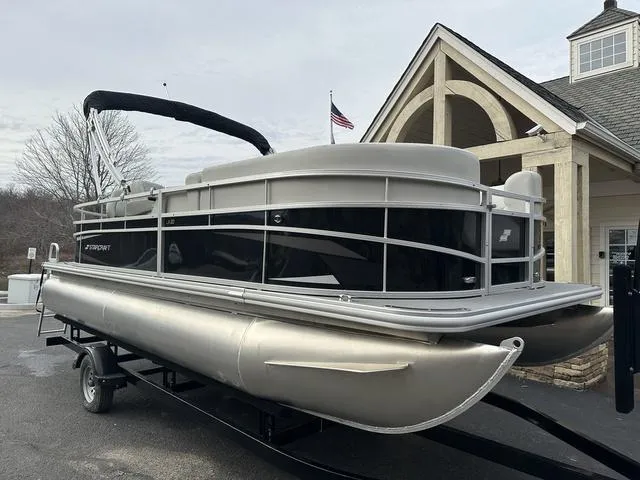 Slide: The Image of 2024 Starcraft LX 20 F pontoon boat on trailer, parked near a building. - 4