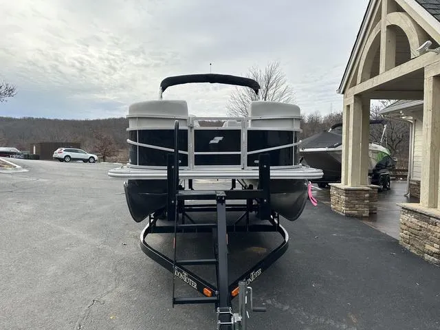 Slide: The Image of 2024 Starcraft LX 20 F pontoon boat on trailer, parked near a building. - 6