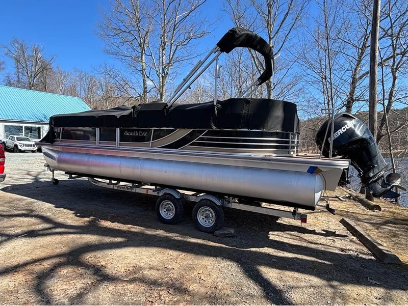Slide: The Image of 2014 South Bay 523E pontoon boat on trailer, parked outdoors with trees and blue sky. - 1