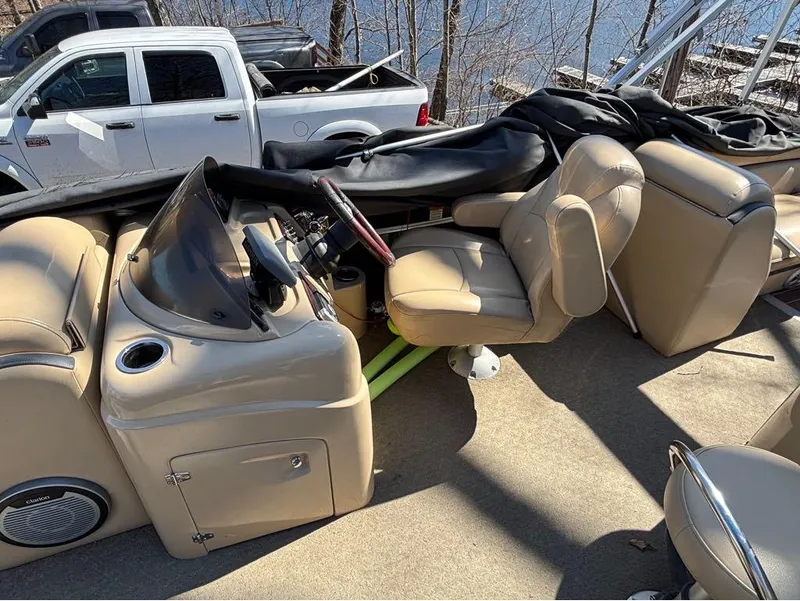 Slide: The Image of Pontoon boat interior with beige seating, steering console, and a white truck in the background. - 5
