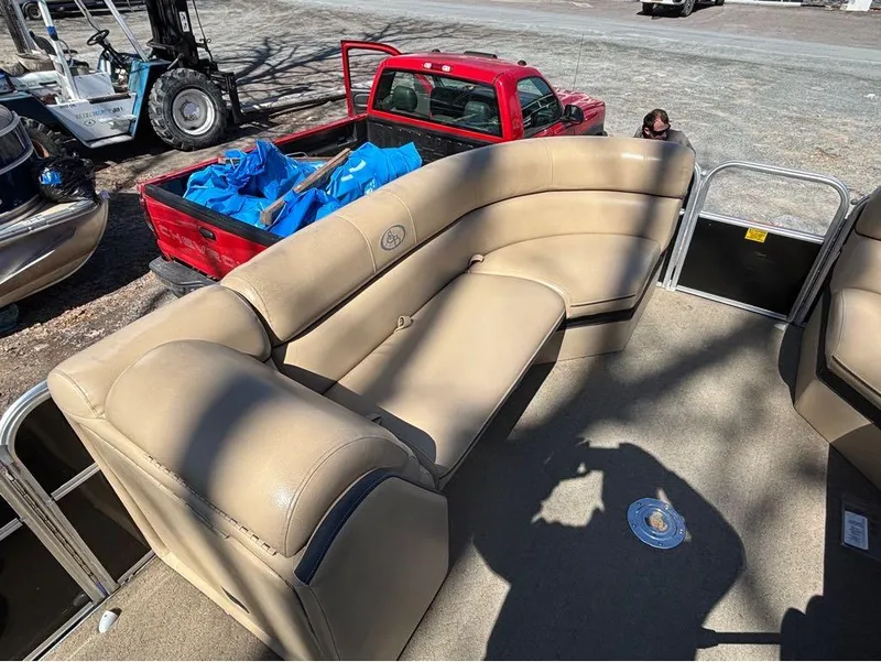 Slide: The Image of 2014 South Bay 523E pontoon boat with beige seating, parked near a red truck. - 8