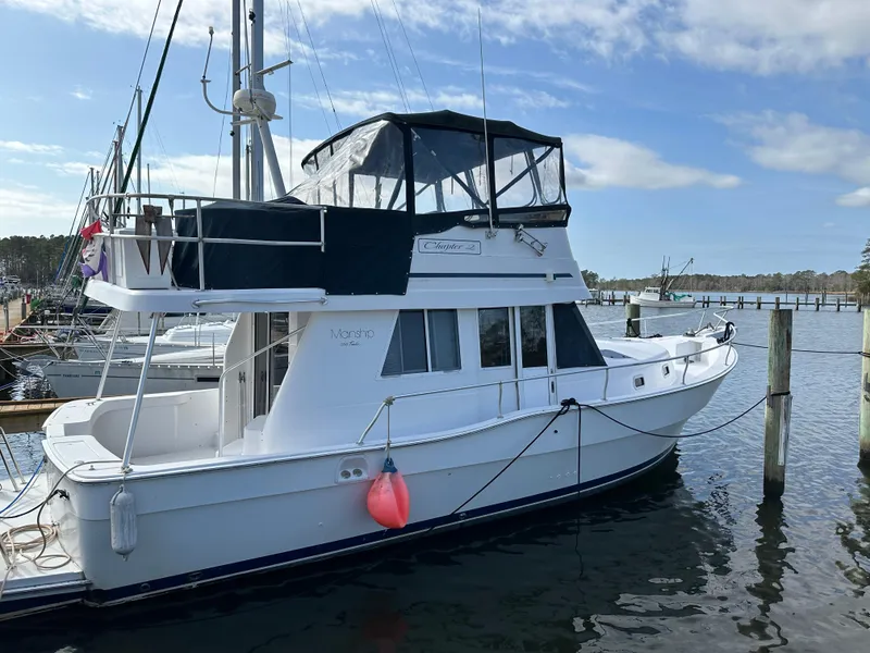 The Image of 1998 Mainship 350 Trawler docked at marina under blue sky. - 1