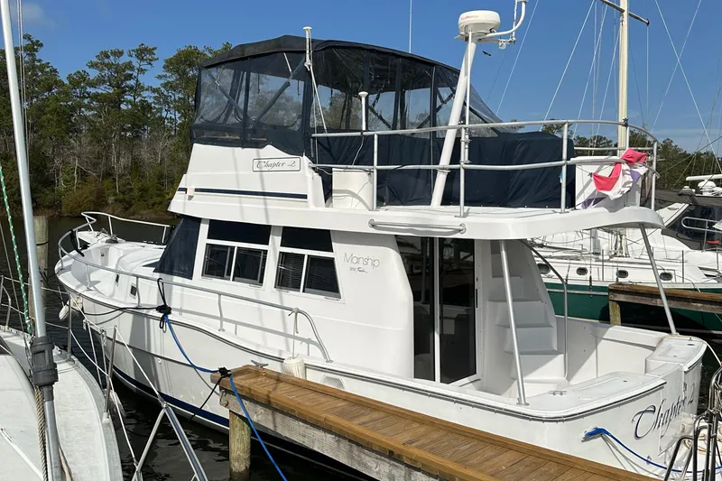 Slide: The Image of 1998 Mainship 350 Trawler docked, featuring spacious deck and covered flybridge. - 10