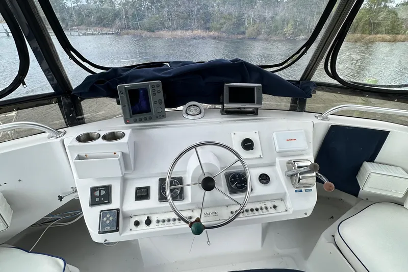Slide: The Image of 1998 Mainship 350 Trawler helm with steering wheel, navigation instruments, and water view. - 16