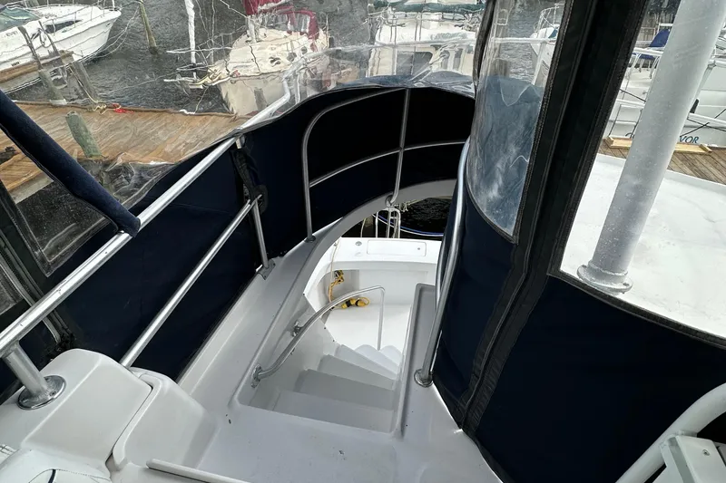 Slide: The Image of 1998 Mainship 350 Trawler staircase with blue canvas enclosure at marina. - 20