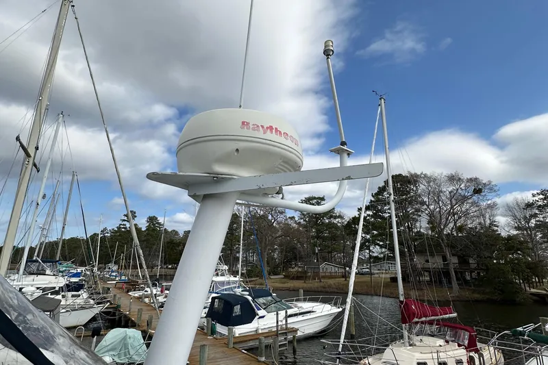 Slide: The Image of 1998 Mainship 350 Trawler docked, featuring Raytheon radar, surrounded by sailboats under cloudy sky. - 24