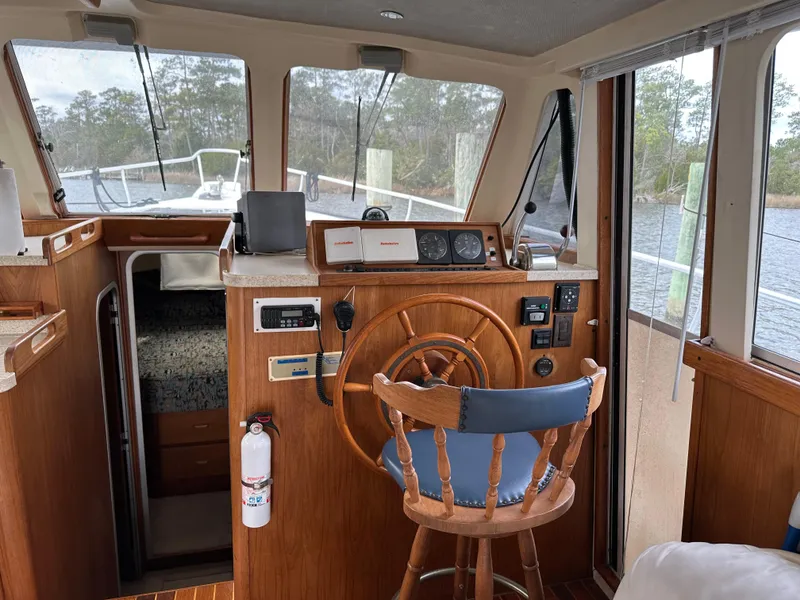 Slide: The Image of 1998 Mainship 350 Trawler helm with wooden wheel, navigation instruments, and cozy cabin interior. - 26