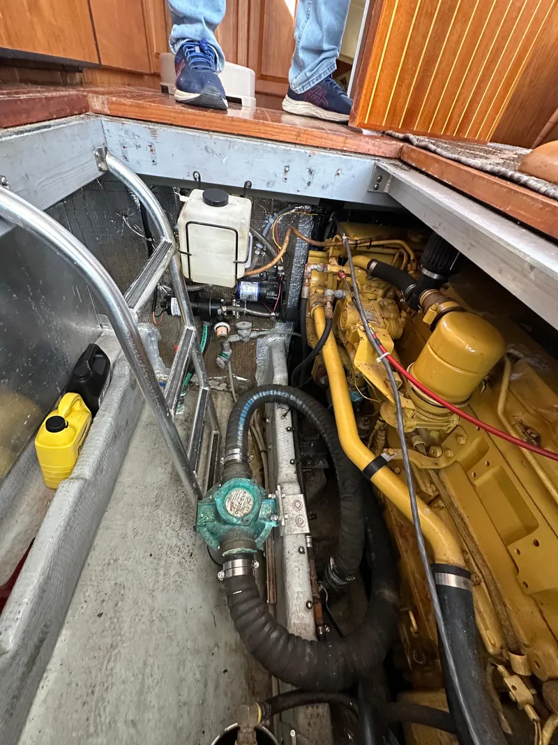 Slide: The Image of Engine compartment of a 1998 Mainship 350 Trawler, showcasing mechanical components and piping. - 27