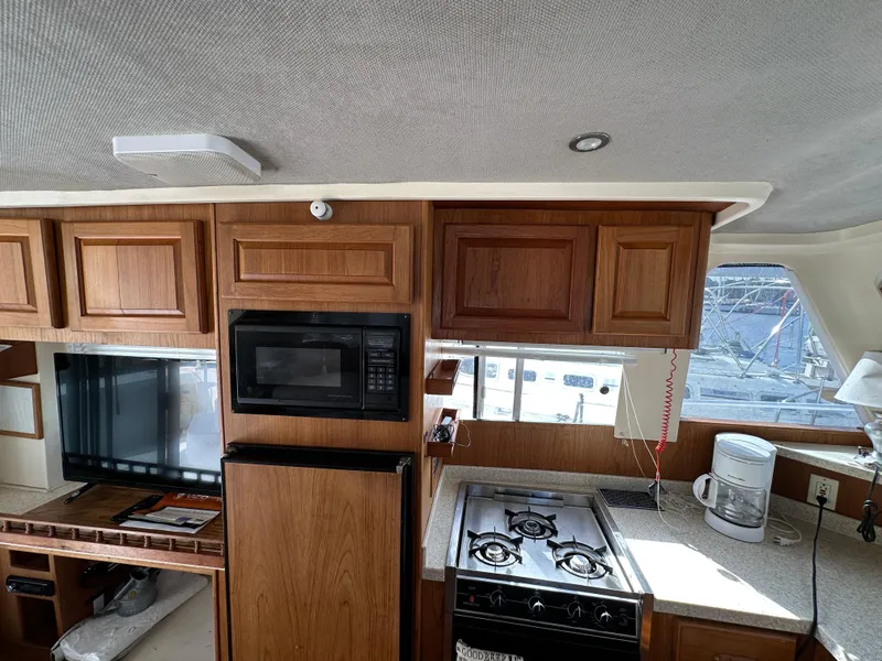 Slide: The Image of 1998 Mainship 350 Trawler kitchen with wood cabinets, stove, microwave, and countertop appliances. - 35
